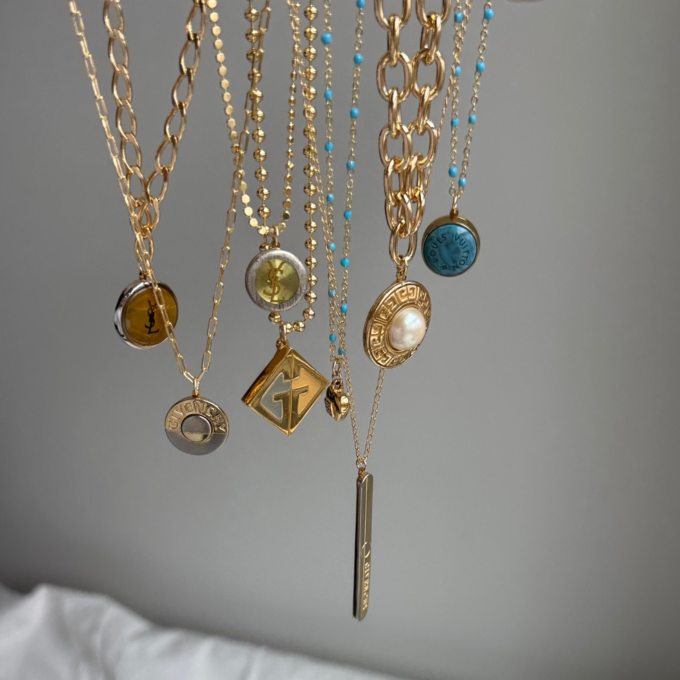 Close-up of a handcrafted repurposed vintage green YSL pendant necklace on a gold-filled, high-shine chain. Featuring an authentic Saint Laurent charm, this unique piece merges timeless luxury with modern elegance, perfect for everyday wear or layering.