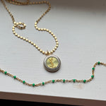 Close-up of a handcrafted repurposed vintage green YSL pendant necklace on a gold-filled, high-shine chain. Featuring an authentic Saint Laurent charm, this unique piece merges timeless luxury with modern elegance, perfect for everyday wear or layering.