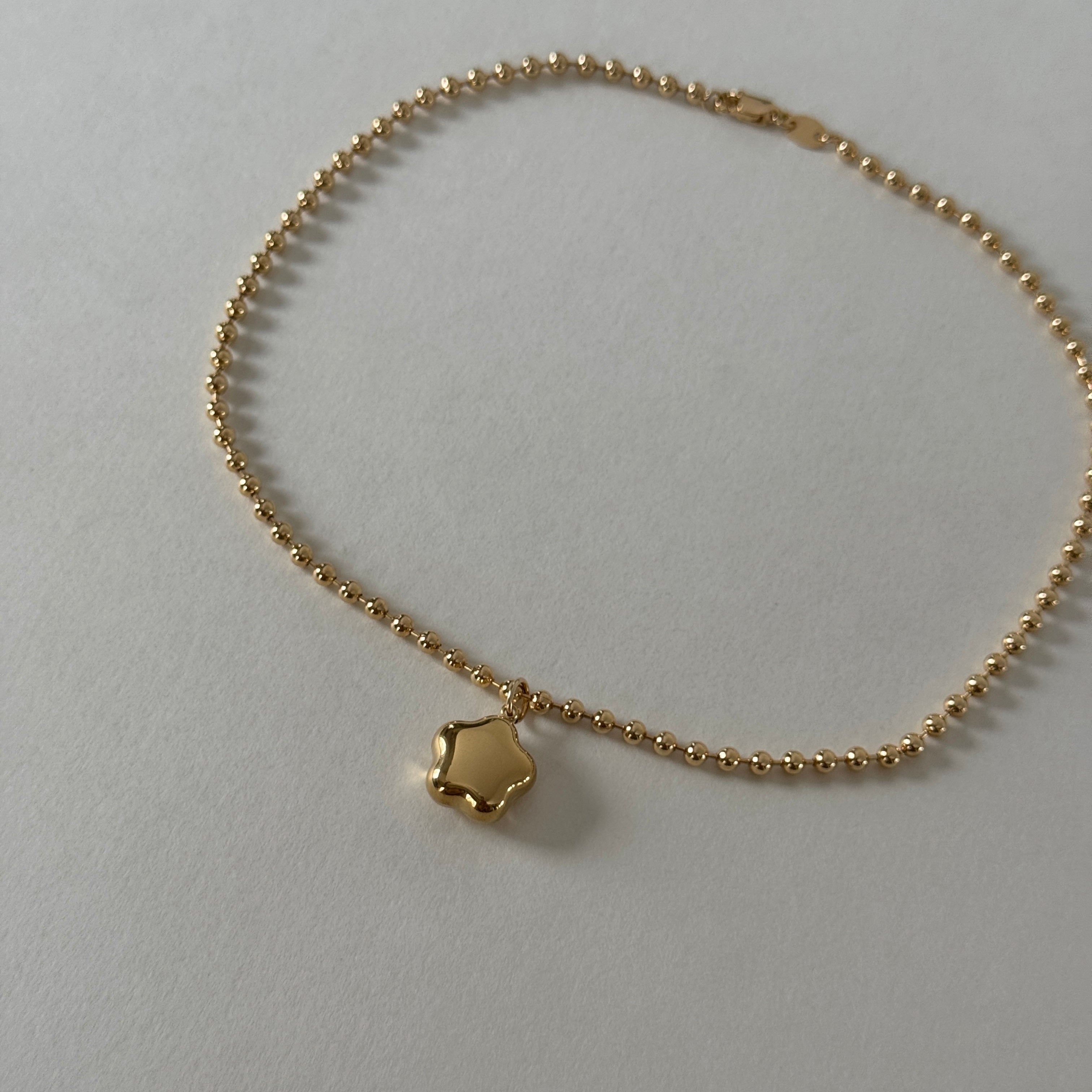 A gold-colored choker necklace with a star-shaped pendant, displayed against a light background.