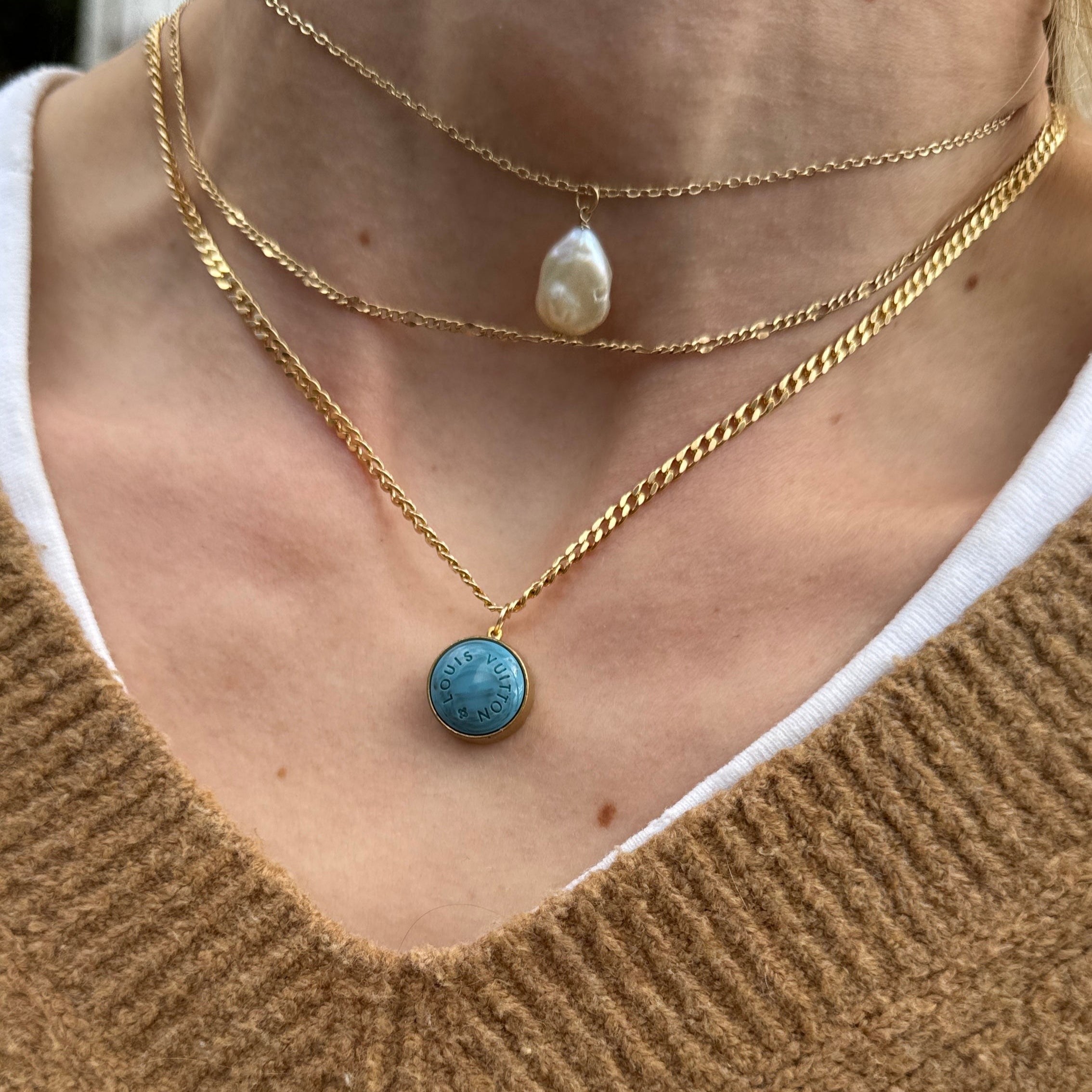 Close-up of a vintage Louis Vuitton turquoise pendant necklace on a matching dainty blue satellite chain. Featuring an authentic repurposed LV charm, this rare piece blends luxury heritage with modern elegance, perfect for layering or wearing solo.