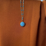 Close-up of a vintage Louis Vuitton turquoise pendant necklace on a matching dainty blue satellite chain. Featuring an authentic repurposed LV charm, this rare piece blends luxury heritage with modern elegance, perfect for layering or wearing solo.