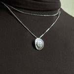 Silver givenchy necklace with a pendant on a black background
