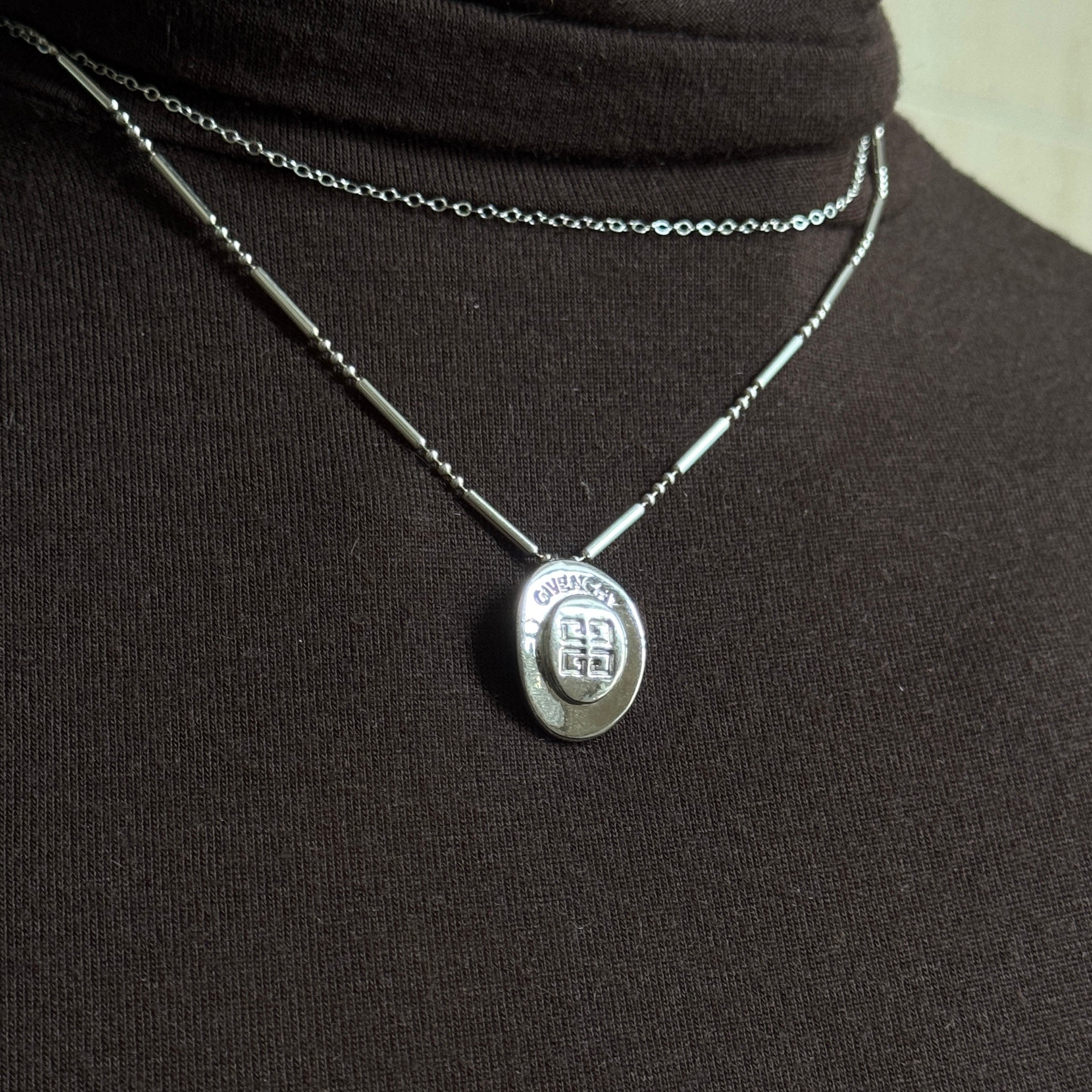 Silver givenchy necklace with a pendant on a black background